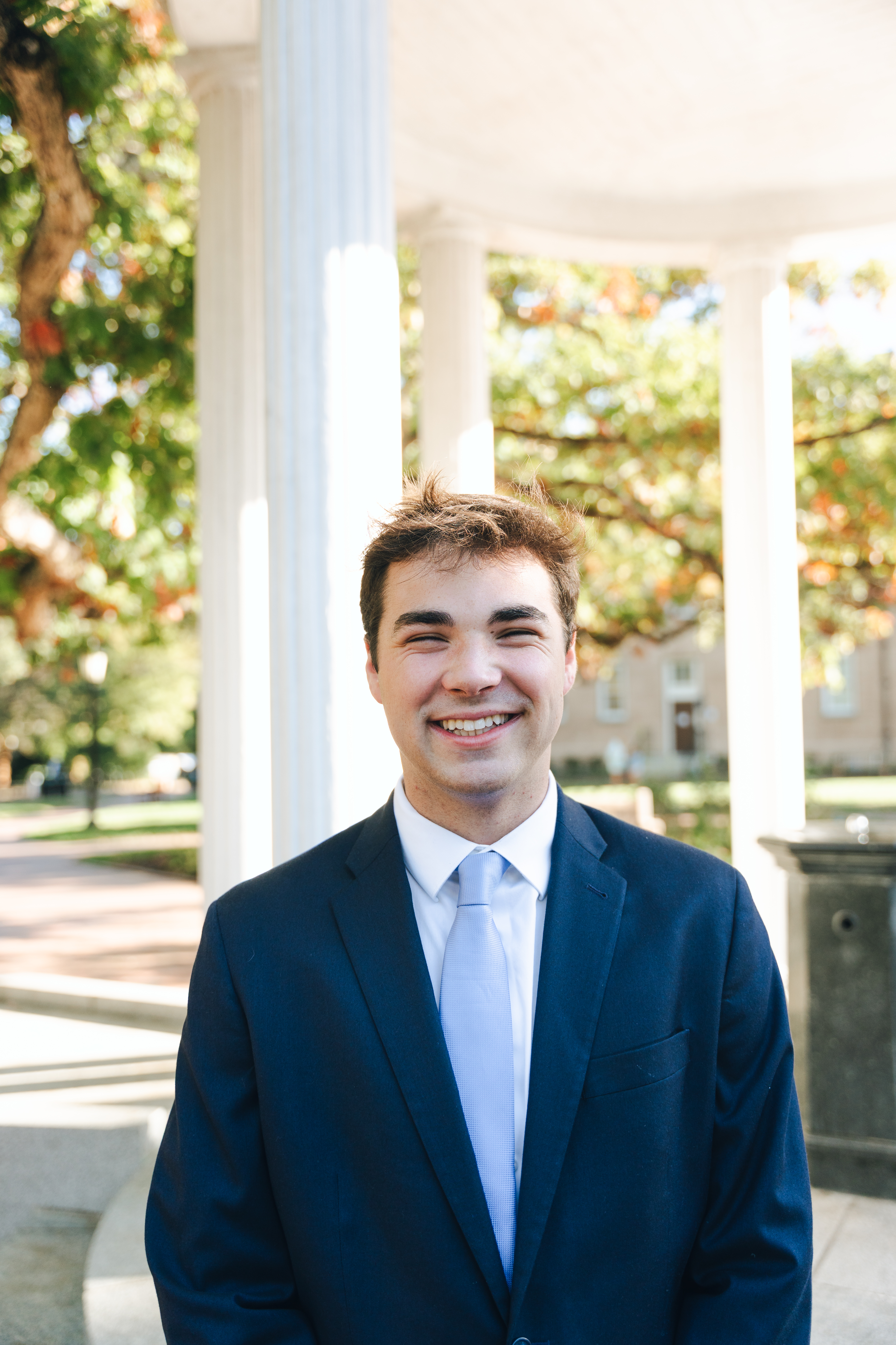 A person stands in front of the Old Well while wearing a suit