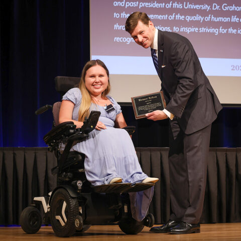 Photo of UNC Chancellor Lee Roberts on stage giving an award to a UNC student during the 2025 Chancellor Awards. The award ceremony took place in the Great Hall of the Carolina Union. Photo Credit: HuthPhoto | Erin Scannell
