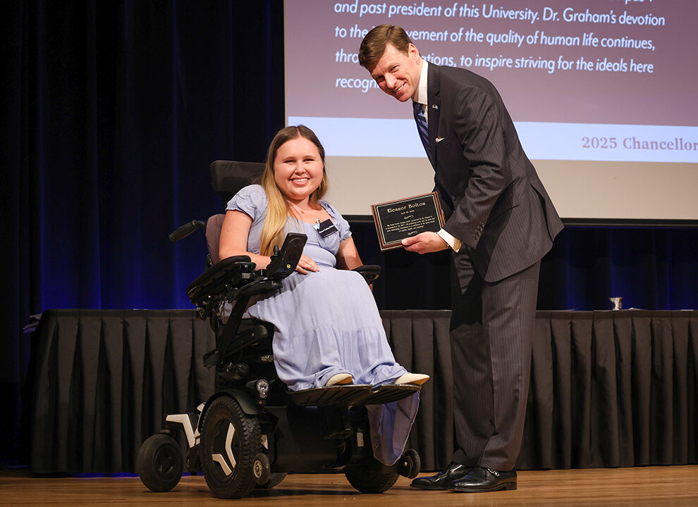 Photo of UNC Chancellor Lee Roberts on stage giving an award to a UNC student during the 2025 Chancellor Awards. The award ceremony took place in the Great Hall of the Carolina Union. Photo Credit: HuthPhoto | Erin Scannell