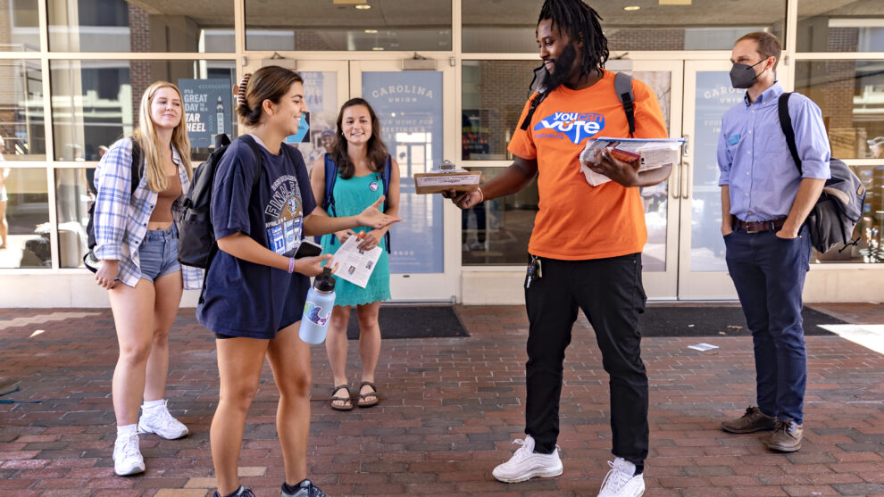 Several students are approached by a voting volunteer outside the Carolina Student Union.