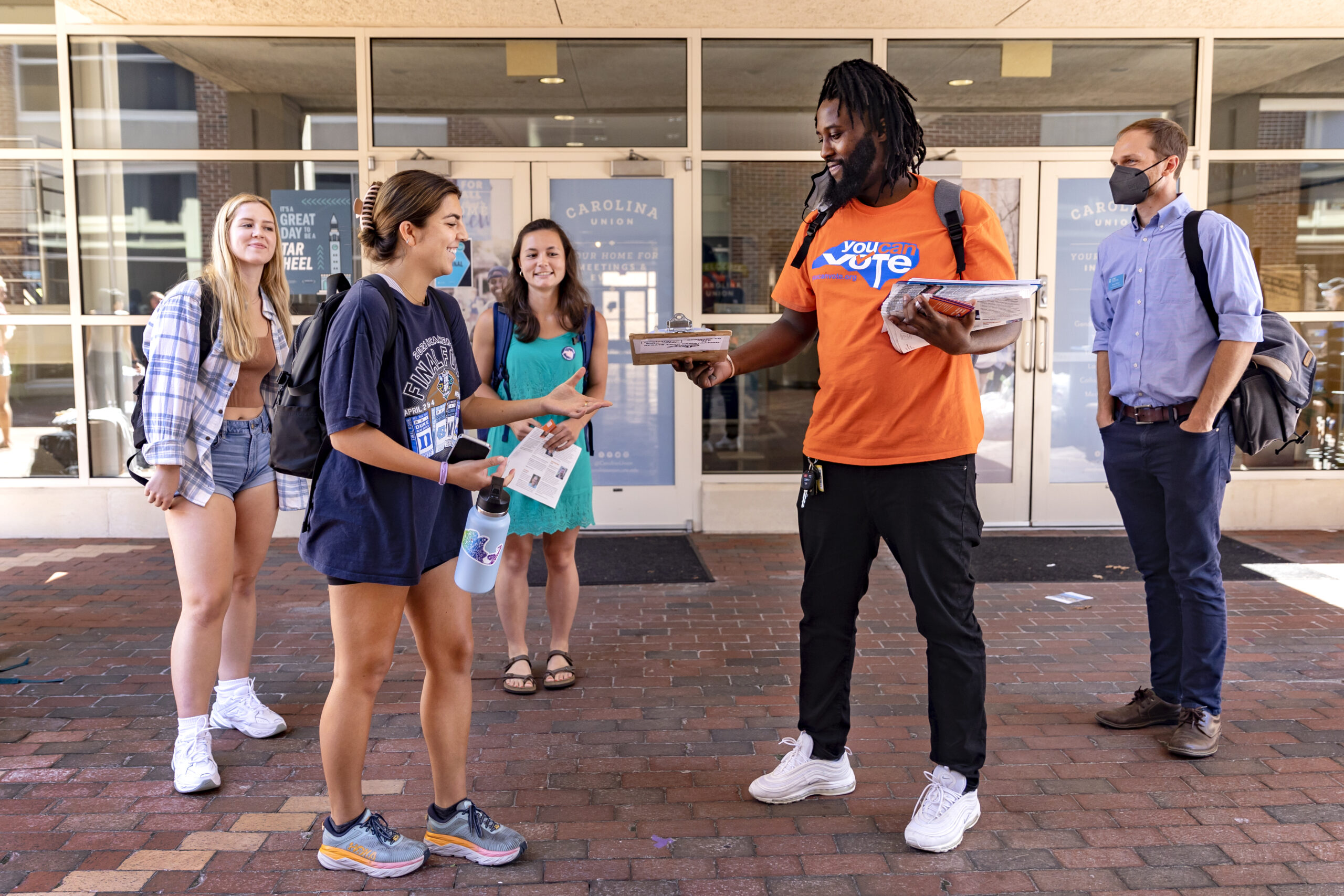 Several students are approached by a voting volunteer outside the Carolina Student Union.