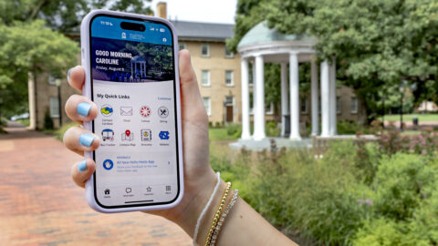 A hand holds a cell phone which is displaying the Hello Heels mobile app.
